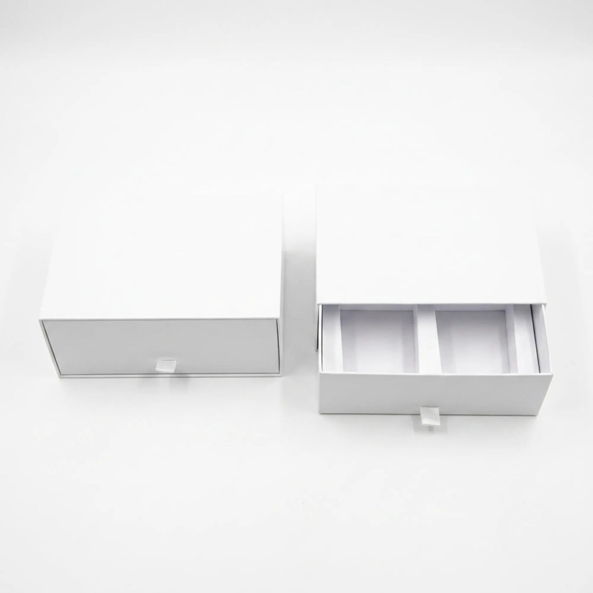 Two white drawer-style packaging boxes on a clean white background, with one closed and one open showing interior compartments.