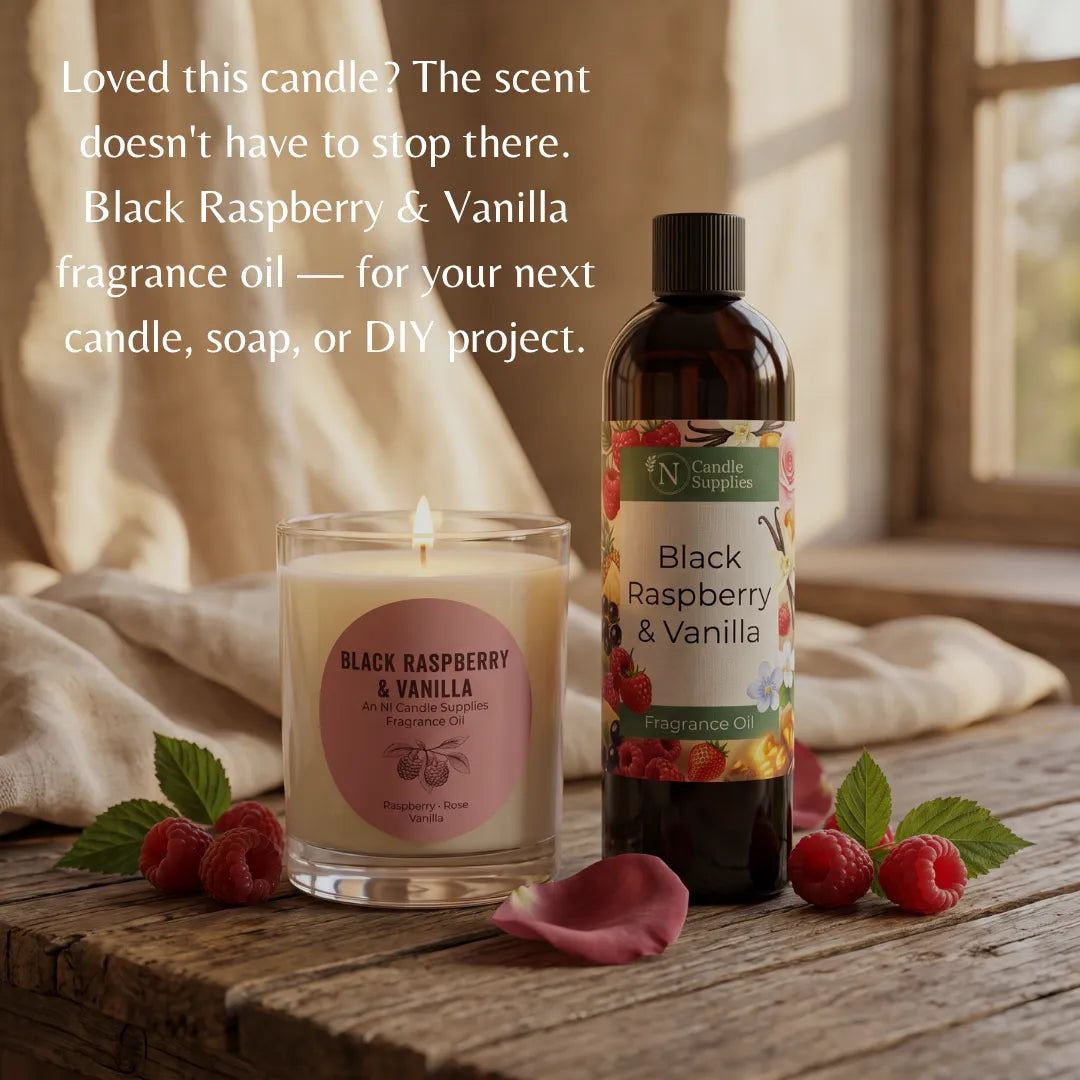 A lit candle and a bottle of fragrance oil from Candle Supplies, both labeled Black Raspberry & Vanilla, arranged on a rustic wooden table with raspberries, mint leaves, and a pink rose petal. Text on the image reads, 'Loved this candle? The scent doesn't have to stop there.