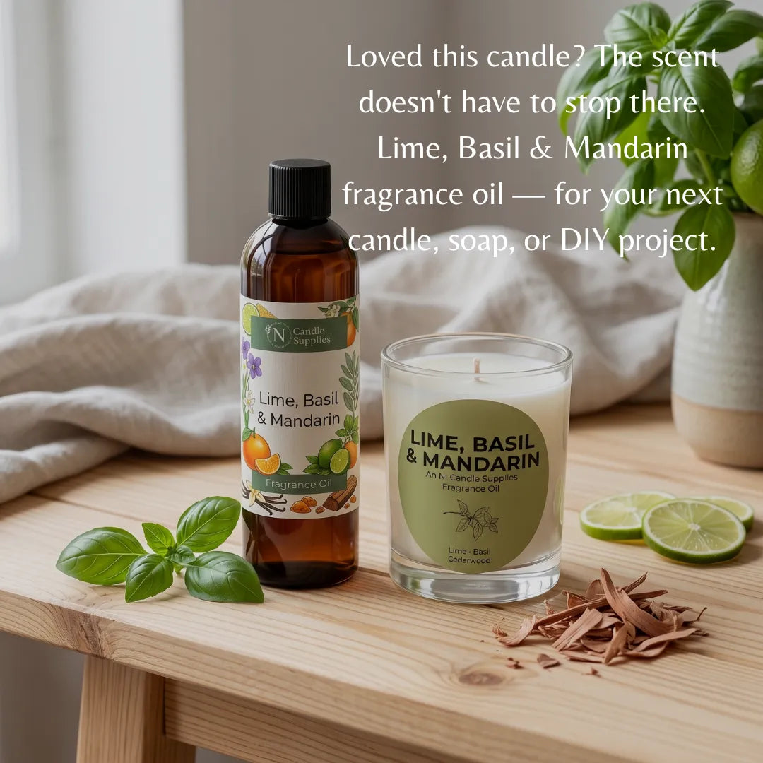 A bottle of Lime, Basil & Mandarin fragrance oil stands next to a matching scented candle in a glass jar on a wooden table. The scene includes basil leaves, lime slices, bark pieces, and soft neutral textiles in the background, with overlaid text promoting the scent for candles, soaps, or DIY projects.
