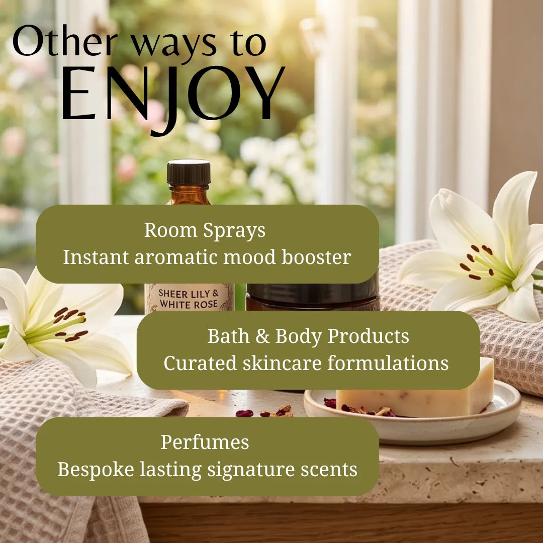 Promotional graphic for a fragrance and wellness product line with text overlays reading 'Other ways to ENJOY' and three callouts for room sprays, bath & body products, and perfumes. A small amber bottle labeled 'Sheer Lily & White Rose' sits on a tabletop with white lilies and a soap dish in a softly lit indoor setting.
