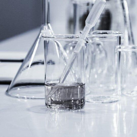 Reed diffuser sticks absorbing fragrance liquid in glass beaker during home fragrance product preparation