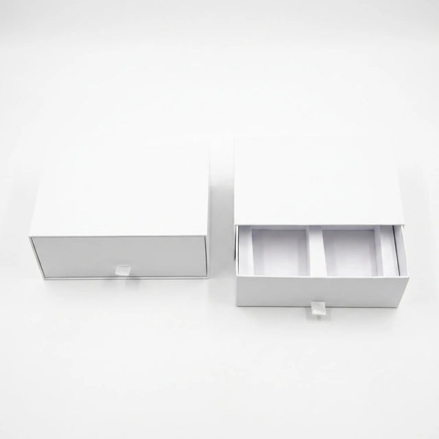 Two white drawer-style packaging boxes on a clean white background, with one closed and one open showing interior compartments.