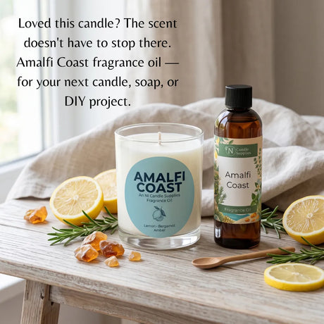 Amalfi Coast fragrance oil shown in a clear glass bottle and a white candle jar, styled on a wooden table with lemon slices, rosemary, amber cubes, and a cloth backdrop. Text at the top reads, 'Loved this candle? The scent doesn't have to stop there.