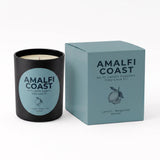 A black candle jar with a light blue circular label next to its matching light blue box, both printed with the brand name AMALFI COAST and scent name Lemon Bergamot Amber.