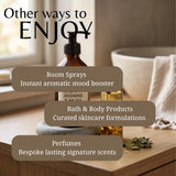An amber glass pump bottle labeled 'JASMINE & MUSK' sits on a wooden surface in a softly lit bathroom-like setting, with overlaid text reading 'Other ways to ENJOY' and callouts for room sprays, bath & body products, and perfumes.