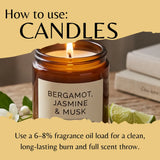 A candle in an amber jar with a cream label that reads Bergamot, Jasmine & Musk. Large text reads 'How to use: CANDLES' and smaller text explains loading of 6-8% fragrance oil for a long-lasting burn and full scent throw.