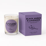 A glass jar candle with cream-colored wax and a purple circular label next to its purple packaging box, both labeled 'BLACK AMBER & LAVENDER' by An NI Candle Supplies.
