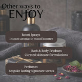 Promotional graphic for a fragrance and body product collection, featuring a dark bottle with a gold pump, a jar labeled BODY SCRUB, and gift packaging on a gray towel with rose petals. Large text reads 'Other ways to ENJOY' with callouts for room sprays, bath & body products, and perfumes.