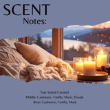 Scent profile graphic for a candle, titled 'SCENT Notes:' with a warm cozy scene of lit candles, pillows, and a knitted blanket in front of a window. Text lists the fragrance notes: Top: Salted Caramel, Middle: Cashmere, Vanilla, Musk, Woods, and Base: Cashmere, Vanilla, Musk.