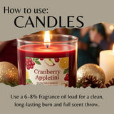 A lit red scented candle in a clear glass jar with a Cranberry Appletini label, shown in a styled holiday scene with ornaments and pinecones. Large text at the top reads 'How to use: CANDLES' and text at the bottom explains fragrance oil load usage.