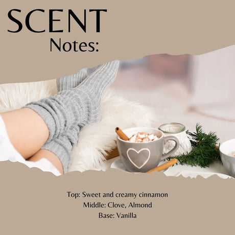 Scent Notes graphic for a cozy hot cocoa fragrance, featuring a person's legs in gray socks next to a mug of hot cocoa with marshmallows, a cinnamon stick, and green pine sprigs. Text lists the scent profile as Sweet and creamy cinnamon, Clove, Almond, and Vanilla.