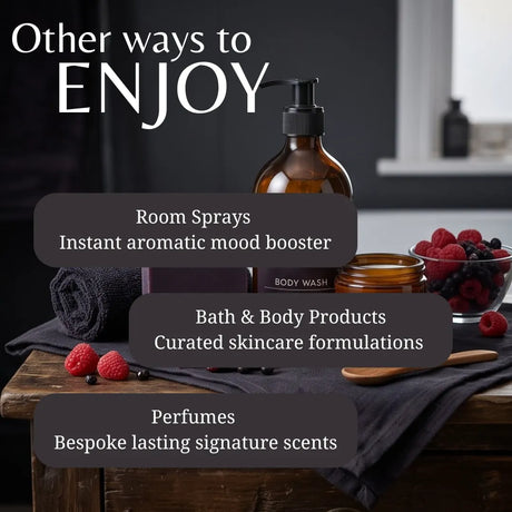 Promotional graphic for a body wash product, showing an amber pump bottle labeled BODY WASH on a rustic wooden table with dark towels, raspberries, and text overlays reading 'Other ways to ENJOY' plus room sprays, bath & body products, and perfumes.