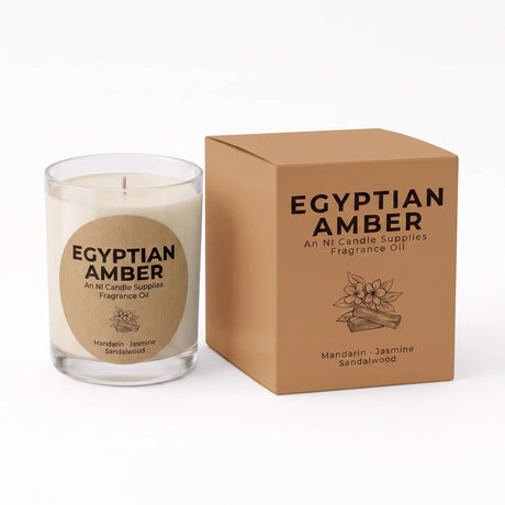A clear glass jar candle with cream-colored wax and a round kraft paper label reading 'EGYPTIAN AMBER', shown next to its matching brown cardboard box on a white background.