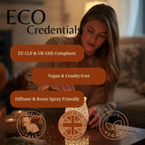 A woman in a cozy room is shown holding a glowing decorative candle diffuser. Large text reads 'ECO Credentials' with callout bubbles stating 'EU CLP & UK GHS Compliant', 'Vegan & Cruelty-Free', and 'Diffuser & Room Spray Friendly', plus circular badges for cruelty-free, UK made, and vegan-friendly.