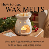 A ceramic wax warmer with star cutouts and a lit tealight candle, shown on a wooden surface with pine branches, red berries, and text reading 'How to use: WAX MELTS' and 'Use a 10% fragrance oil load in your wax melts for deep, long-lasting aroma.'.