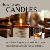 An informational graphic titled 'How to use: CANDLES' shows a lit amber glass jar candle labeled 'Irish Whiskey Soy Candle' on a table, with a glass of whiskey and a blurred interior background. Text at the bottom explains fragrance oil load usage.