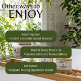 Promotional graphic for a bath and body product collection, featuring three text callouts over a lifestyle scene of a wooden tray holding a bath oil bottle, bath salts, and a handmade soap bar in a bright bathroom with green plants.