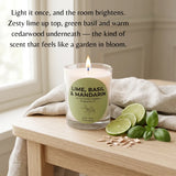 A lit scented candle in a clear glass jar sits on a light wood table beside lime slices, basil leaves, and small wood shavings, with a draped linen cloth and a softly blurred indoor background. Text on the image reads: 'Light it once, and the room brightens.