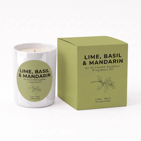 A white glass candle jar with a green circular label next to its matching olive green box, both labeled 'LIME, BASIL & MANDARIN' fragrance oil by An NI Candle Supplies.