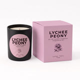 A black candle jar with a pink circular label next to its matching pink box, both printed with the text 'LYCHEE PEONY' and a rose illustration, on a white background.