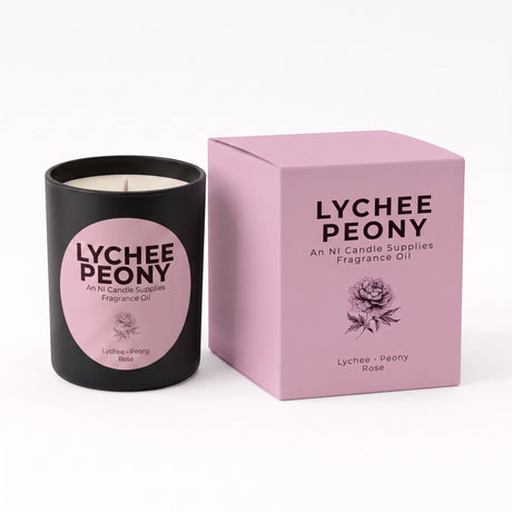 A black candle jar with a pink circular label next to its matching pink box, both printed with the text 'LYCHEE PEONY' and a rose illustration, on a white background.