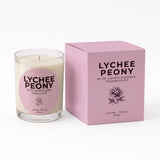 A Lychee Peony fragrance oil candle in a clear glass jar with cream-colored wax and a pink circular label, shown next to its matching pink square box on a white background.