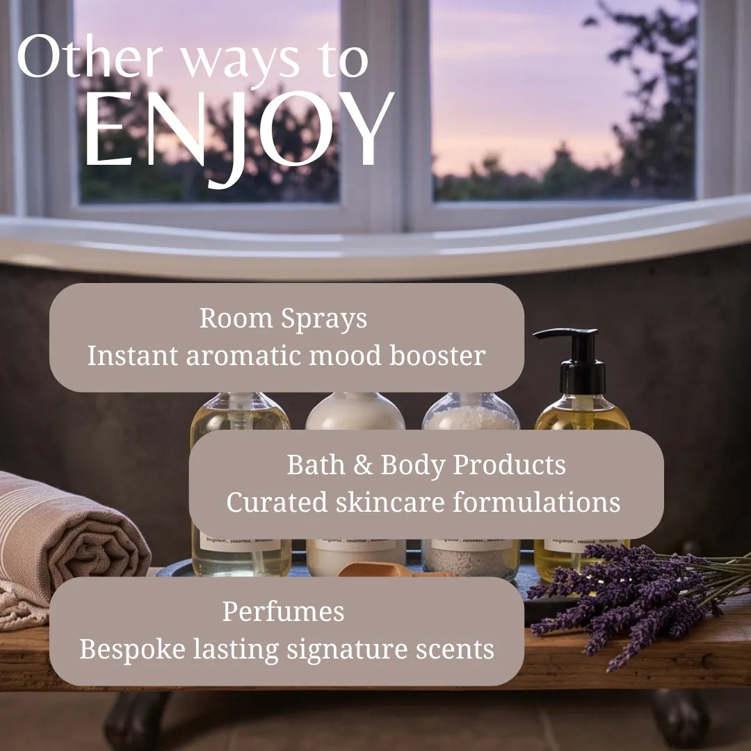 Promotional graphic for a bath and body product collection, featuring several clear bottles with amber liquids and black pumps arranged on a wooden surface next to lavender sprigs and a rolled towel. Large text reads 'Other ways to ENJOY' with callouts for Room Sprays, Bath & Body Products, and Perfumes, set against a softly blurred window and bathtub background.