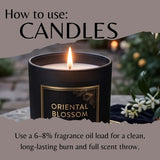 A lit black scented candle labeled 'ORIENTAL BLOSSOM' with text reading 'How to use: CANDLES' and usage instructions below, set against a softly blurred outdoor background with greenery and flowers.