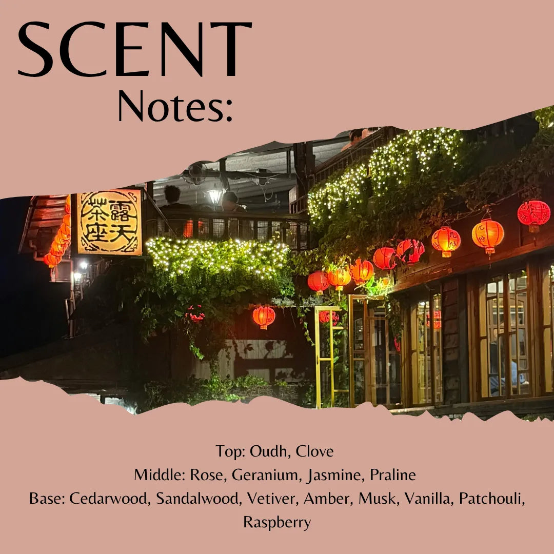 A scent profile graphic with the title 'SCENT Notes:' on a dusty pink background, featuring a nighttime photograph of a lantern-lit street scene with greenery and red lanterns. Text at the bottom lists fragrance notes: Top: Oudh, Clove; Middle: Rose, Geranium, Jasmine, Praline; Base: Cedarwood, Sandalwood, Vetiver, Amber, Musk, Vanilla, Patchouli, Raspberry.