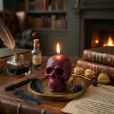 Skull-shaped candle on a wooden table with books, feathers, and a bottle labeled 'Witches' Brew'.