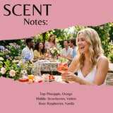 Pink graphic with the title 'SCENT Notes:' and a torn-paper photo of a woman at an outdoor garden table holding a pink drink. Text below lists scent notes: Top: Pineapple, Orange; Middle: Strawberries, Violets; Base: Raspberries, Vanilla.