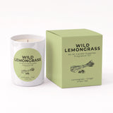 A white candle jar labeled 'WILD LEMONGRASS' next to its light green box, with the scent notes 'Lemongrass + Ginger' and 'Green Tea' visible on both the label and packaging.