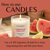 A lit scented candle in a clear glass jar labeled 'Summer Spritz Watermelon Lemonade' sits on a table with watermelon slices and a lemon wedge, under a coral banner that reads 'How to use: Candles' and includes usage text about fragrance oil load.