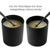 Two black candles with wick dippers in them on a white background.